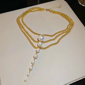 Detailed macro view of multi-layered gold pearl necklace with tiered white pearls