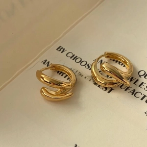 Macro shot of gold layered spiral hoop earrings on a minimalist book background