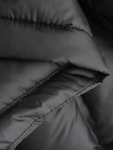 Detailed macro view of dark grey quilted fabric for women's fashion padded vest