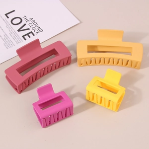 Set of four matte rectangle hair claws in pink and yellow on a neutral background