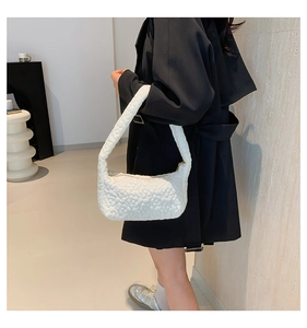 Detail of white dumpling bag showing 3D floral texture on minimalist shoulder strap bag