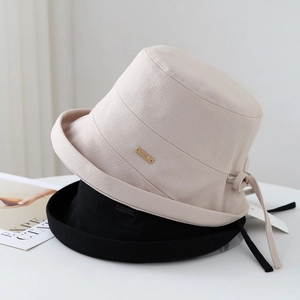 Elegant beige and black cotton linen bucket hats with ribbon bows and metal logos