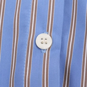 Detalle de la tela de rayas verticales con botones blancos de cuatro agujeros en la camisa