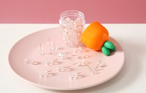 Close-up of clear push pins in a pink tray with a cute carrot-shaped storage container