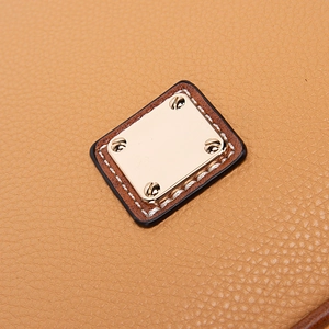 Close-up of brown pebble grain leather handbag texture with gold square metal hardware