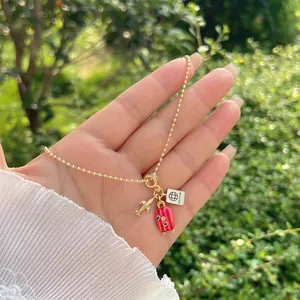 Dettaglio collana a catena a sfere in oro 18K con ciondoli aereo, passaporto e valigia