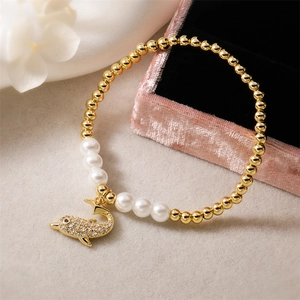 Dettaglio del bracciale con delfino, perle dorate e ciondolo in zirconi pavé