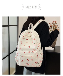 Detailed back view of white corduroy backpack with red cherry embroidery and straps