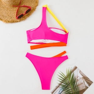 Vista piatta di un bikini rosa monospalla con spalline colorate e accessori per le vacanze