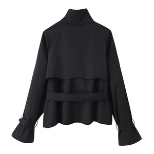 Detail of black cropped trench jacket showing back storm flap and belted cuffs on white