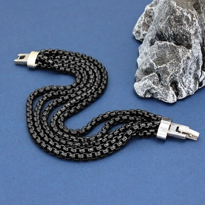 Multi-strand black chain bracelet with silver metal jewelry clasp on blue background