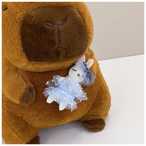 Close-up of brown plush capybara toy wearing a blue mesh skirt bunny pendant detail