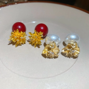 Detail of 18k gold plated earrings featuring red beads and white pearls with crystals