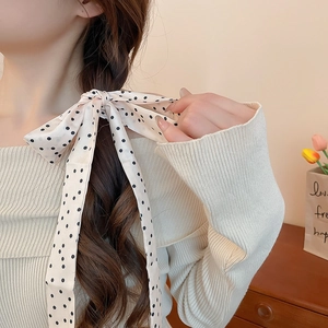 Close-up of a floral silk scarf tied as a bow on a braid, showing soft satin texture