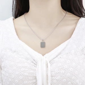 Detail of silver beaded necklace with rectangular pendant worn on a lace outfit
