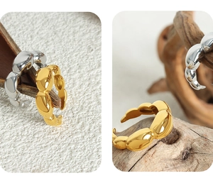 Close-up of geometric oval linked rings in polished gold and silver on wooden branch