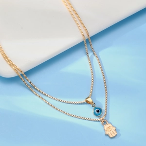 Macro detail of gold layered hamsa hand and evil eye pendant necklaces on boxes