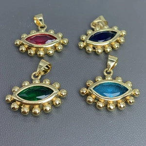 Close-up of four gold-plated evil eye pendants with red, blue, and green crystals