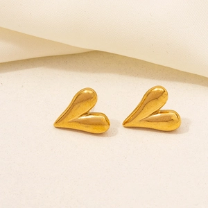Close-up of asymmetrical 18K gold plated heart earrings on soft textured fabric