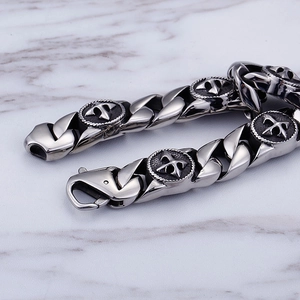 Polished silver stainless steel chain bracelet with a cross charm on marble background