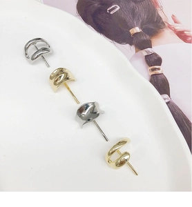 Macro shot of minimalist gold and silver C-shaped metal stud earring accessories on a tray