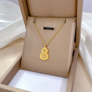 Detailed macro view of a gold gourd pendant with Fu character on white silk background