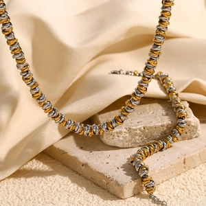 Detail of two-tone gold and silver twisted rope chain resting on decorative stones
