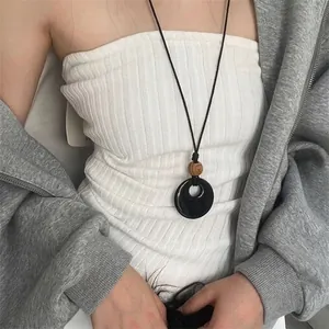Gros plan d'un collier pendentif noir œil de chat avec perle en bois et cordon ciré
