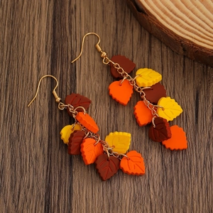 Detail of autumn maple leaf earrings featuring textured orange leaves and gold chain links