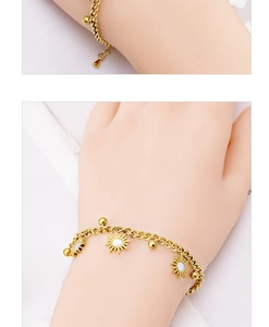 Macro detail of gold-plated bracelet with white sun pendants and beads worn on wrist