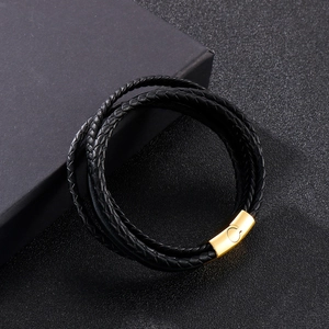 Detailed close-up of multi-layer black braided leather bracelet with golden magnetic clasp