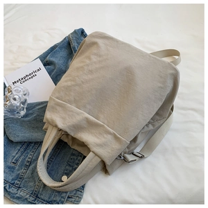 Flat lay of beige nylon backpack with pleated texture and adjustable top handles