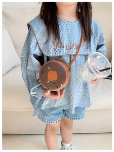 Close-up of a brown doughnut-shaped kids crossbody bag with colorful dots and Hello print