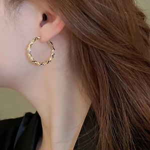 Macro shot of gold geometric hoop earrings with textured crushed silver metal finish