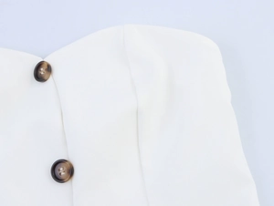 Detail of white tube top vest with tortoiseshell buttons and premium tailored stitching