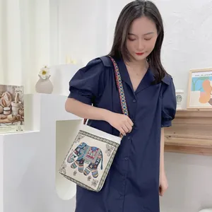 Close-up of ethnic embroidered elephant pattern and woven strap on canvas bag
