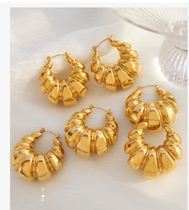 Detail showing vintage golden croissant hoop earrings with a textured threaded metal finish