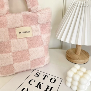 Close-up of pink checkered plush bucket bag with soft texture and brand label