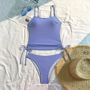 Flat lay of blue striped two-piece swimsuit with drawstring details and summer accessories
