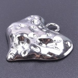 Macro detail of silver stainless steel heart pendant with textured hammered finish