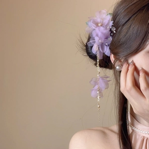 Détail d'une pince à cheveux fleur en tissu violet avec perles et longs glands dorés