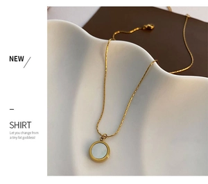 Close-up of mother of pearl pendant on 18K gold plated chain over ceramic plate