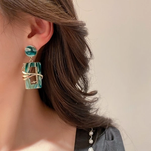 Detail view of vintage green resin earrings with gold metal wrapping worn by a model