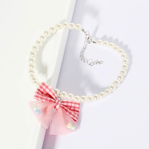 Detail of pet pearl necklace with pink plaid bow on a minimalist geometric stand