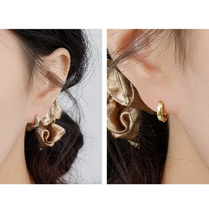 Detail view of twisted geometric hoop earrings in gold and silver finish on model