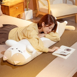 Close-up of a long plush cat pillow used as a soft headboard cushion in a cozy bedroom