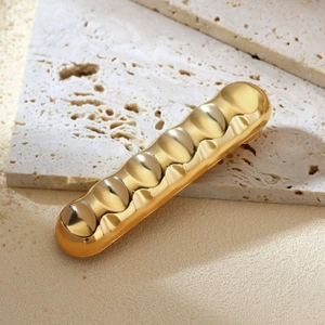Minimalist gold irregular wavy hair clip shown on beige stone tiles for elegant hair styling