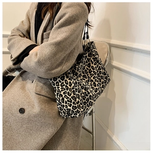 Detail of leopard print canvas tote bag featuring metal rings and black shoulder strap