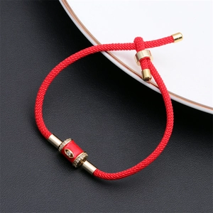 Red adjustable rope bracelet with gold evil eye charm and crystal accents on black leather