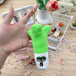 Close-up of a plush green onion keychain with cute embroidery on a wooden table